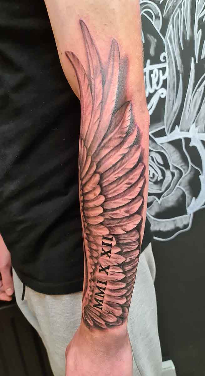 férfi alkar, fekete szárny tetoválás, írás, római számok