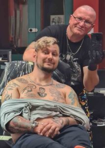 Andris a tetoválószékben Attilával, karján és mellkasán több tetoválással